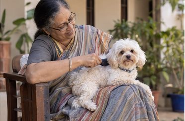 A woman holds a small dog while seated in a chair.
