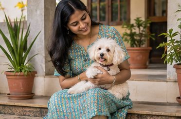 A woman holds a small white dog while seated near a doorway.