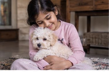 A woman hugs a small white dog while seated on a sofa.