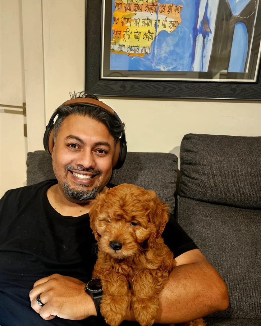 Owner sitting on a sofa with an apricot curly-coated puppy resting against his arm